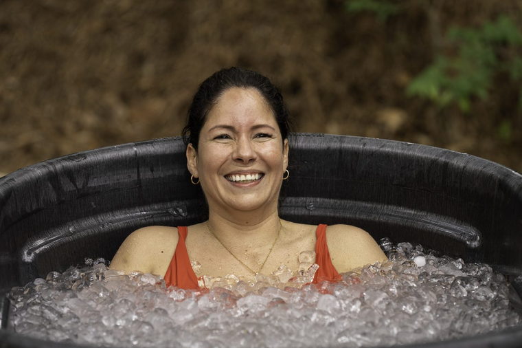 An attendee smiling while sitting chest-deep in an ice bath.