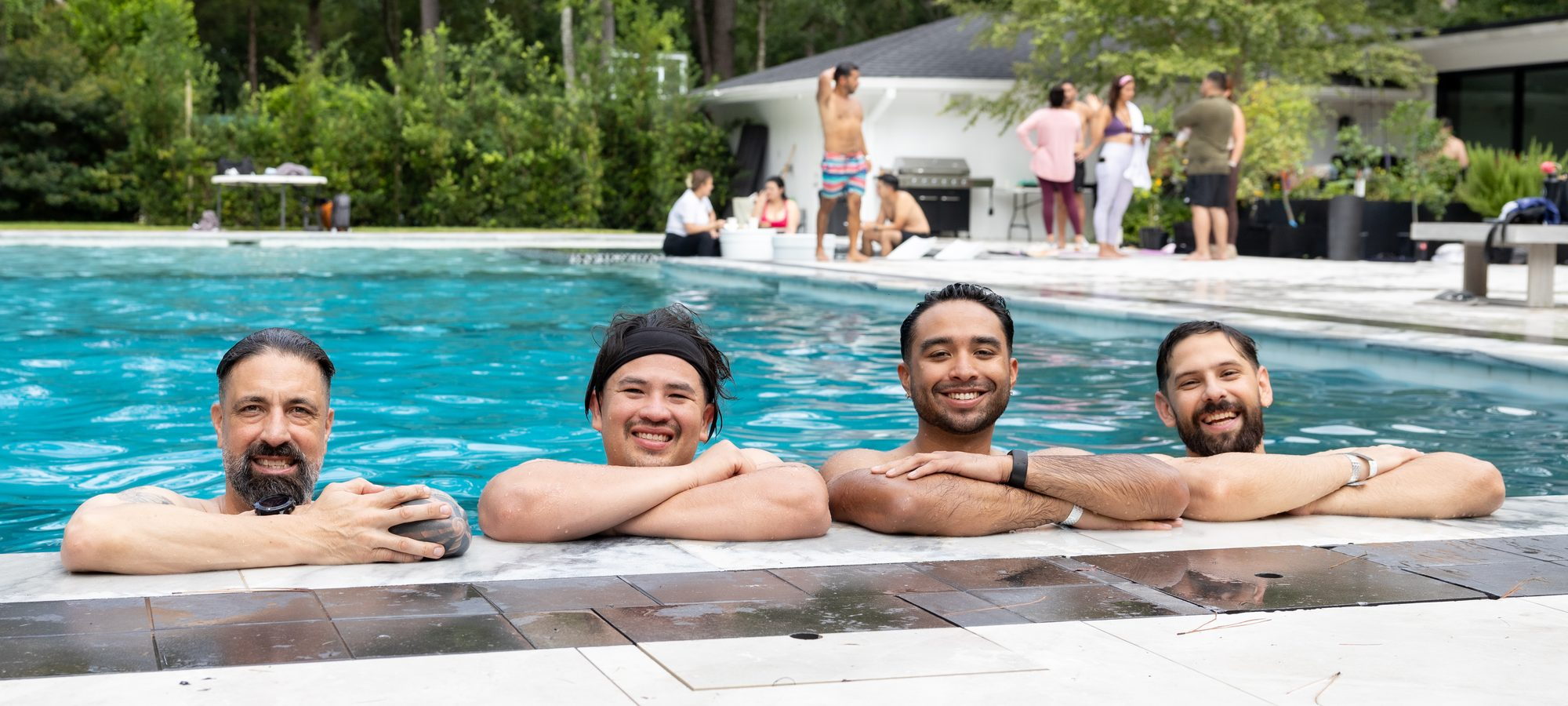 Four people resting at the edge of the pool after a session, the group gathered behind them.
